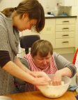 Marie gets her hands in the mix while her support worker steadies the bowl
